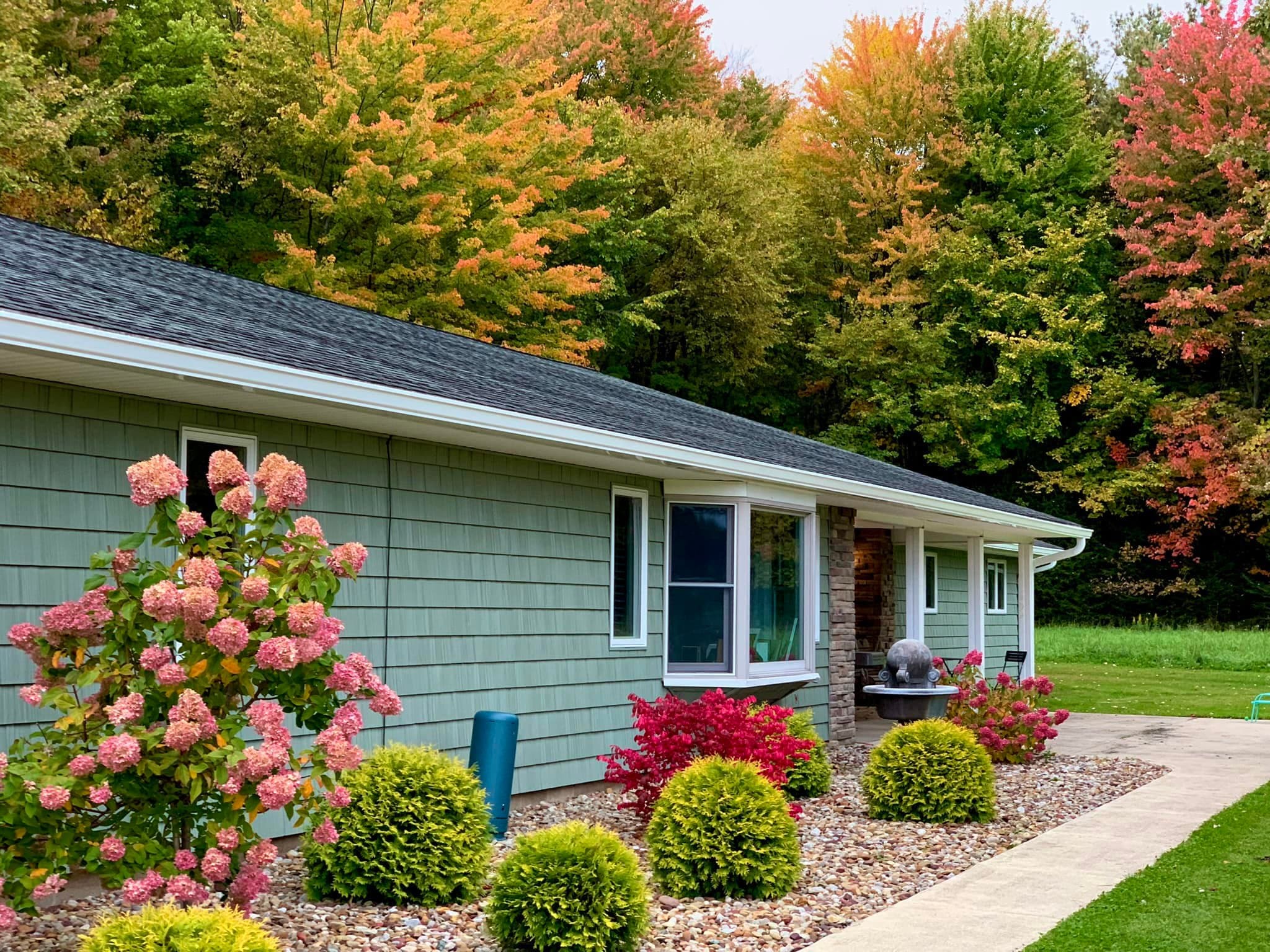 Single-story home with white gutters in front of a line of trees in fall color